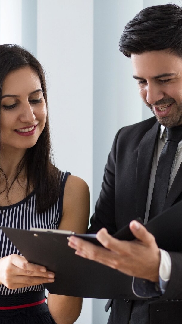 smiling-confident-colleagues-examining-document-together@2x (1)